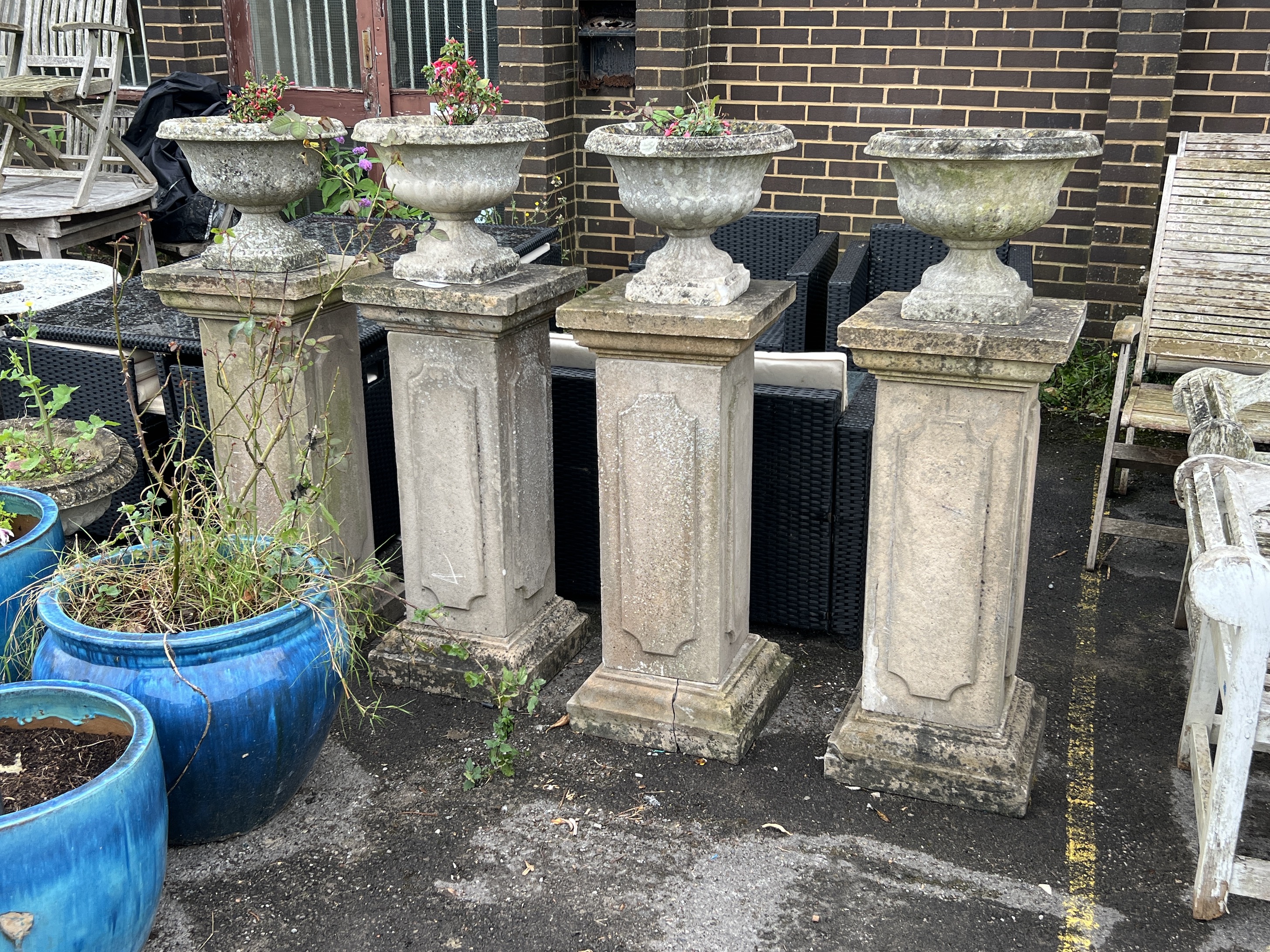 A set of four circular reconstituted stone garden planters on tall square plinths, height 134cm
